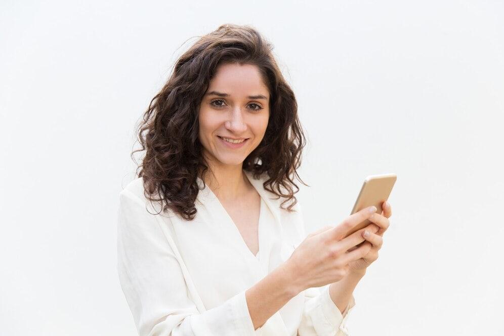 Smiling woman with curly hair checking a claim update on her phone